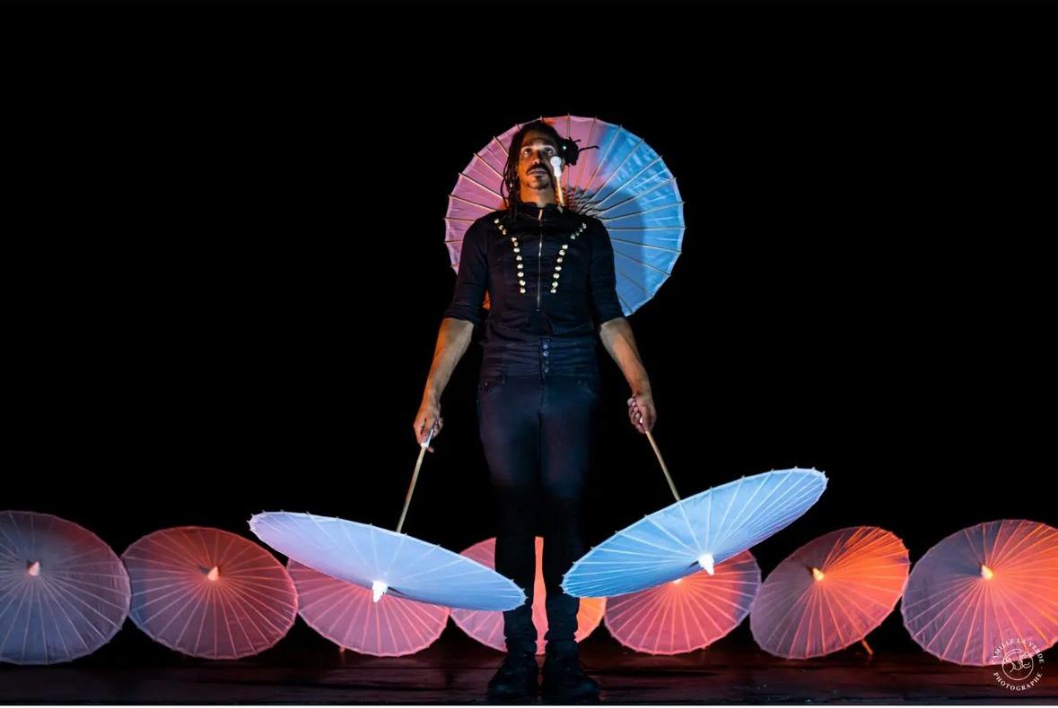 Jean-Souleymane performing with an umbrella in each hand.